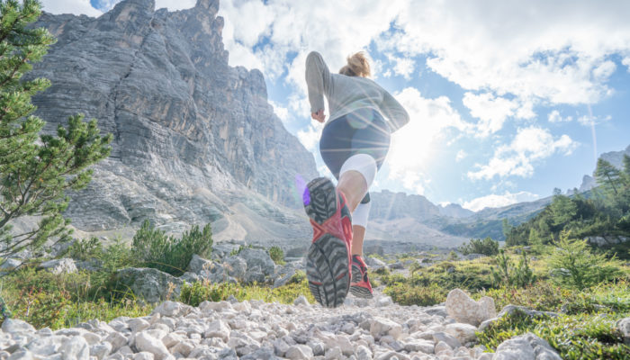 Young fitted woman trail running in the dolomites, Italy Sportive young woman exercising trail running on mountain trail in Alto Adige, Italy. People body conscious and heathy lifestyle concept.